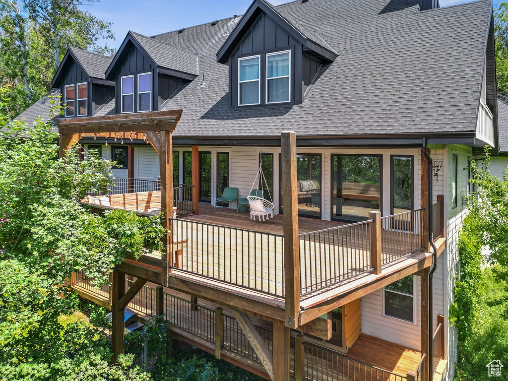Rear view of house featuring roof with shingles, board and batten siding, and a deck