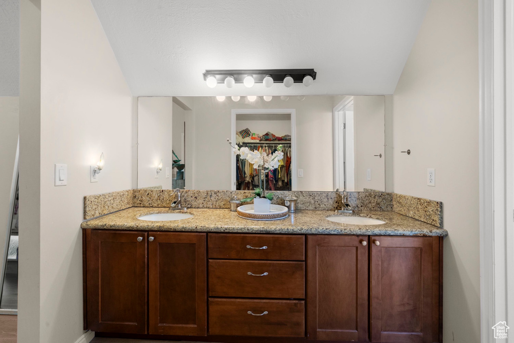 Bathroom featuring double vanity, a walk in closet, and baseboards