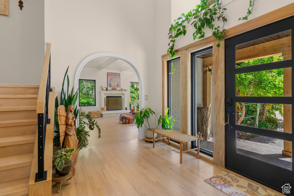 Foyer with wood finished floors, a high ceiling, and a glass covered fireplace