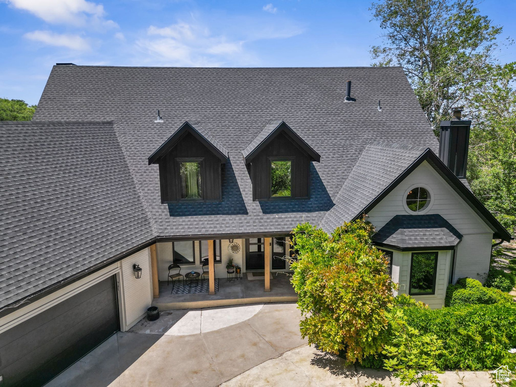 View of front of home featuring a shingled roof and covered porch