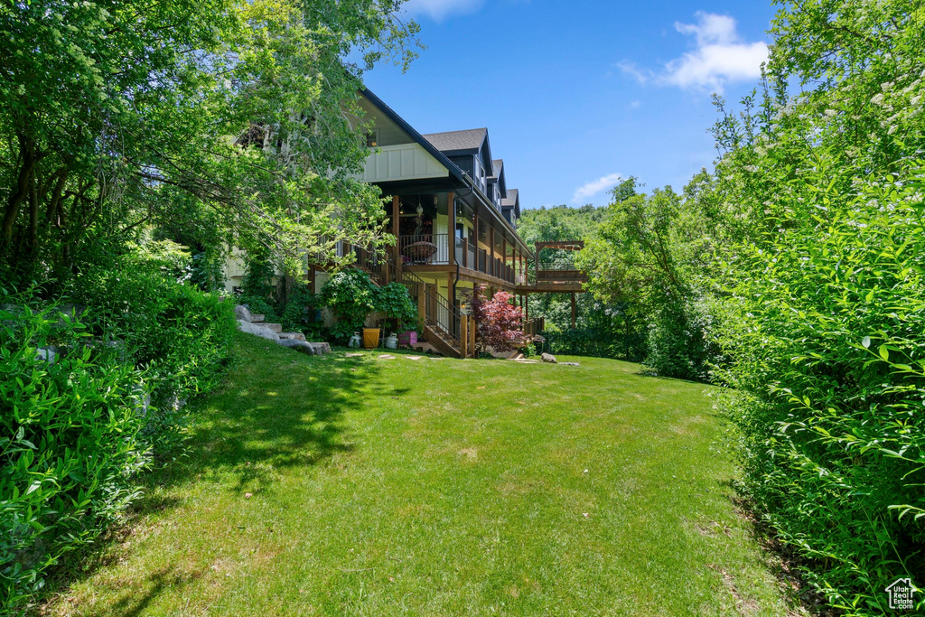 View of grassy yard with stairway and a deck