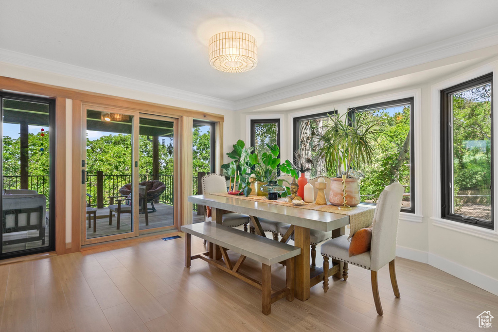 Dining area with light wood-style floors, crown molding, and baseboards