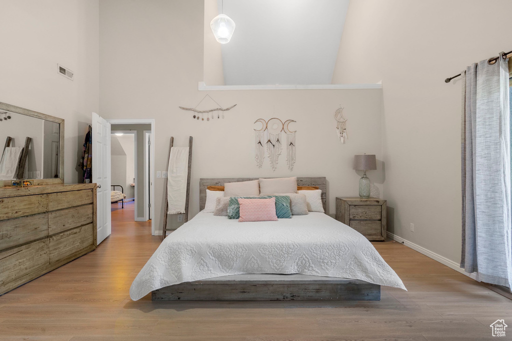 Bedroom featuring a towering ceiling, wood finished floors, and baseboards