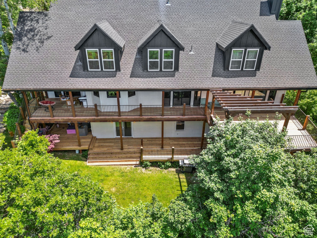 Back of property featuring a shingled roof, a yard, and a balcony