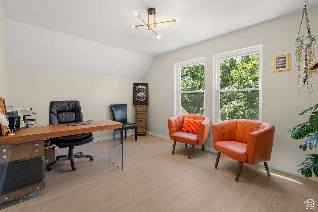Office area featuring lofted ceiling, light wood finished floors, baseboards, and a chandelier