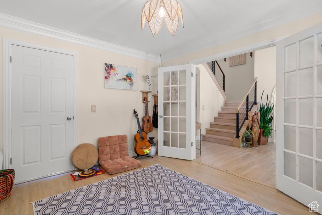 Entryway with french doors, crown molding, wood finished floors, and stairway