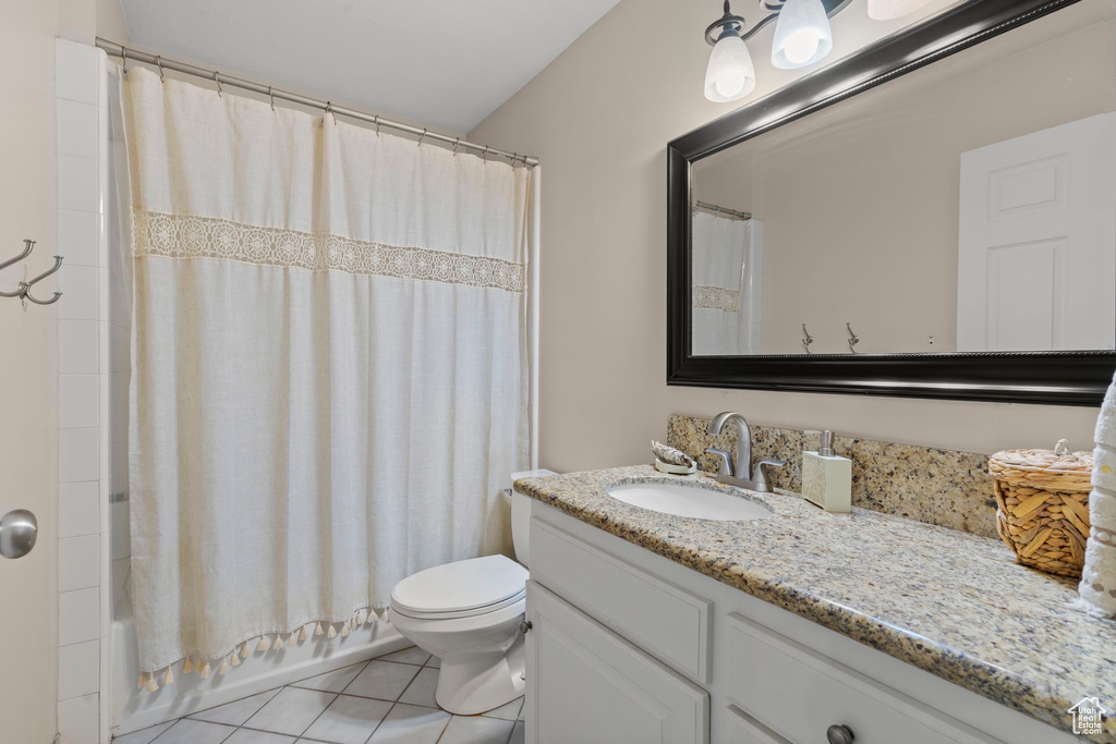 Bathroom featuring vanity, tile patterned floors, toilet, and shower / bath combo with shower curtain