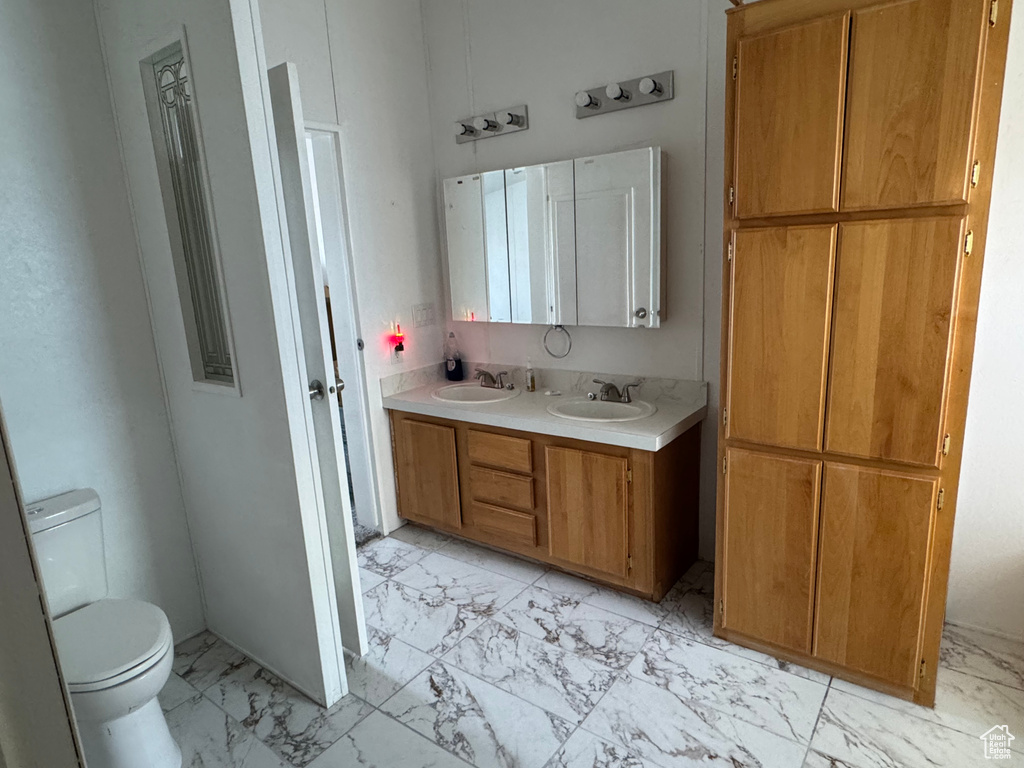 Full bath featuring marble look tile flooring, toilet, and double vanity