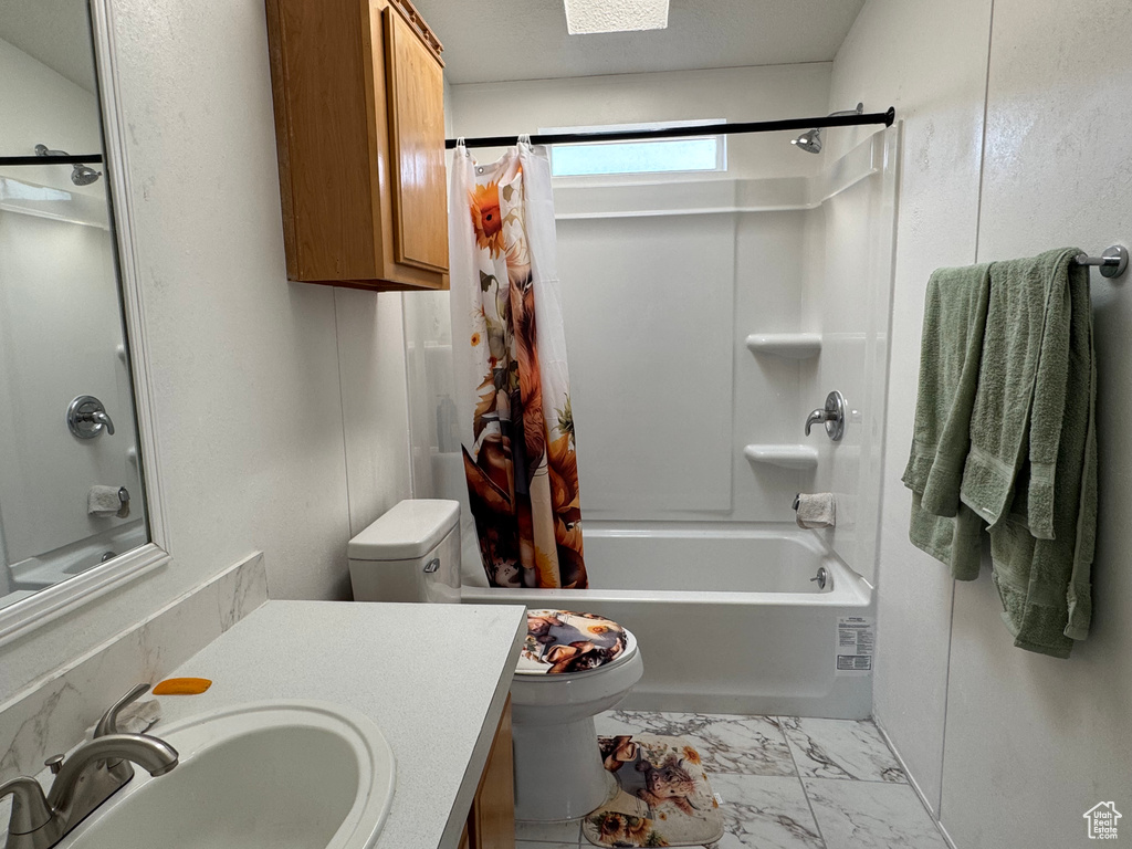 Full bathroom featuring shower / bath combo with shower curtain, toilet, vanity, and marble finish flooring