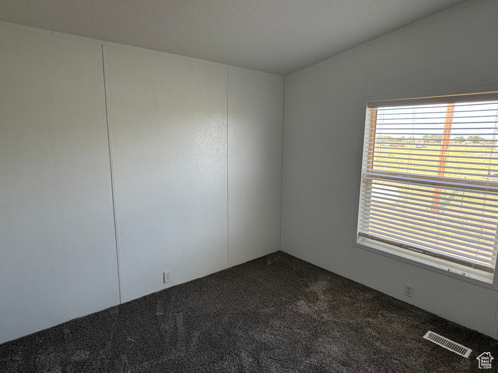 Spare room with dark colored carpet and healthy amount of natural light