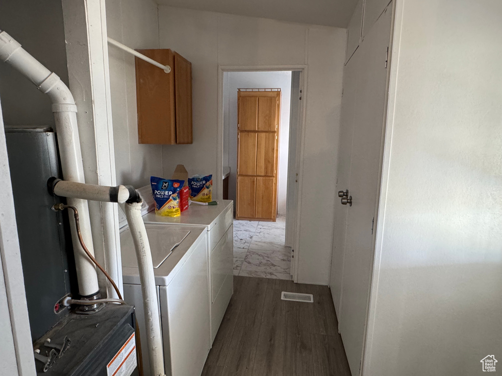 Laundry room featuring independent washer and dryer, wood finished floors, and cabinet space