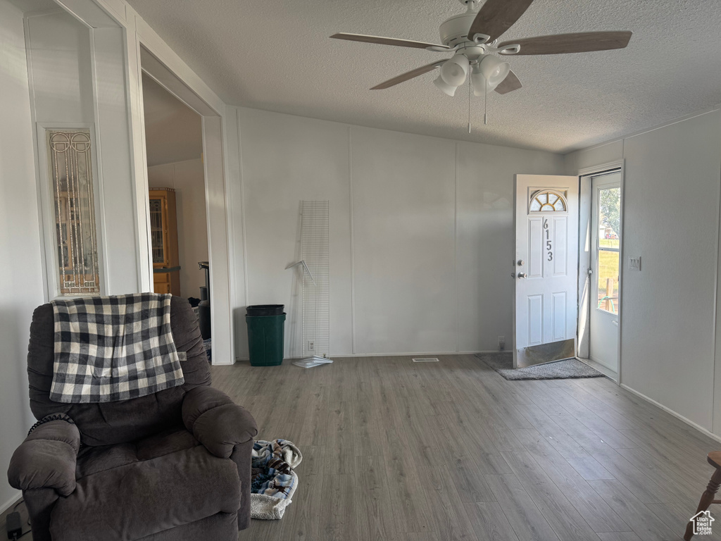 Unfurnished room with a textured ceiling, a ceiling fan, and wood finished floors
