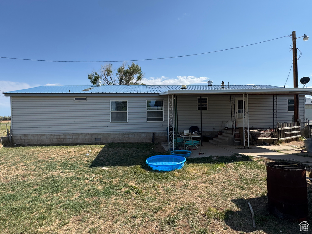 Back of house featuring a lawn, a patio area, and metal roof