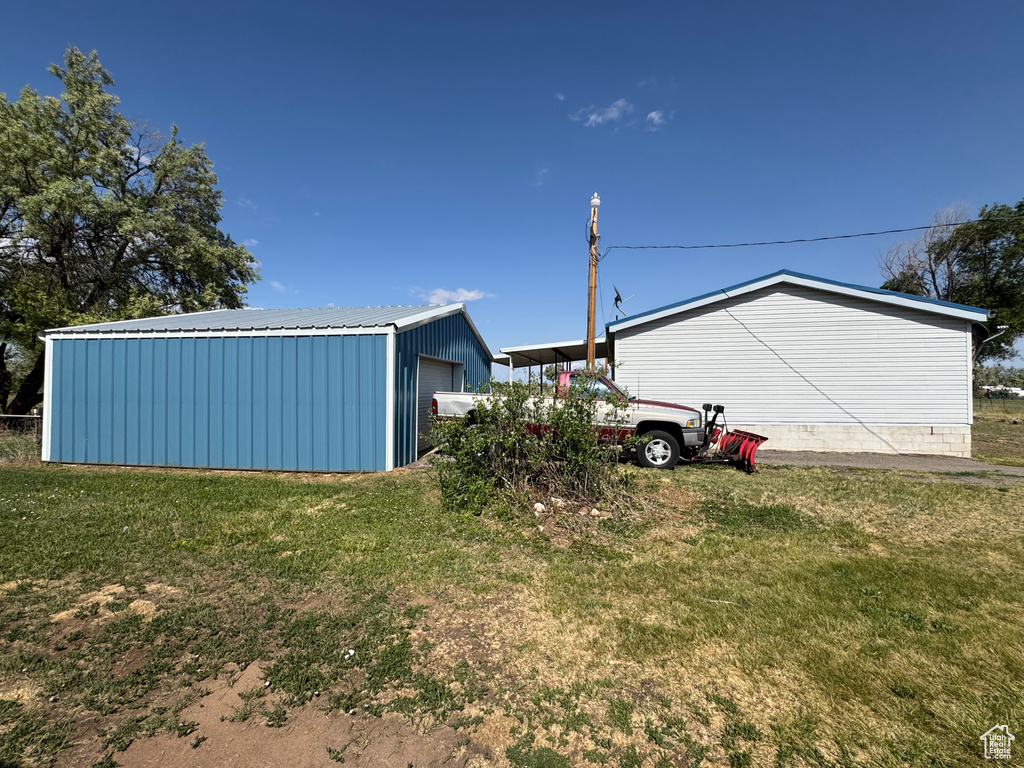 View of green lawn with an outbuilding and a garage