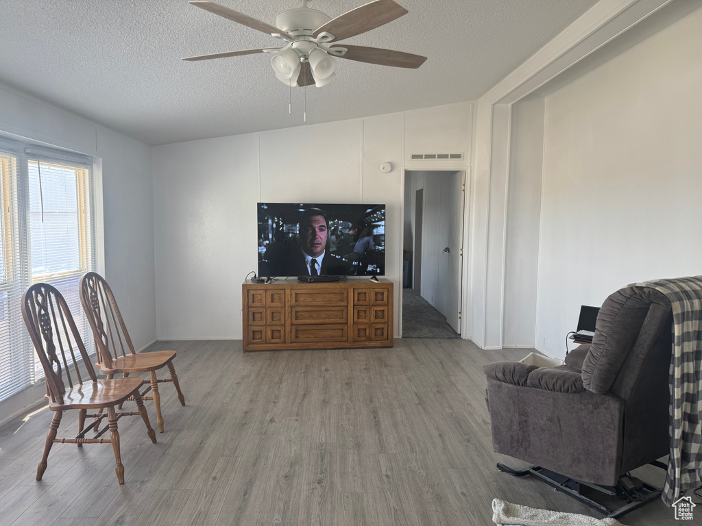 Living area with wood finished floors, ceiling fan, and a textured ceiling