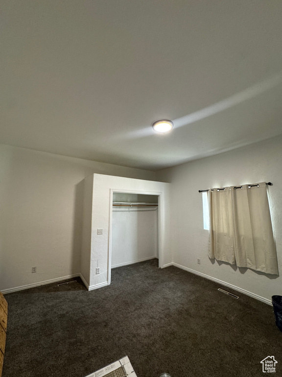 Unfurnished bedroom with dark colored carpet and a closet