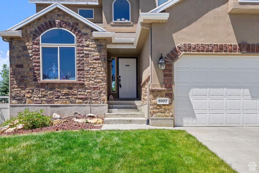 View of front of house with stone siding, an attached garage, stucco siding, and concrete driveway