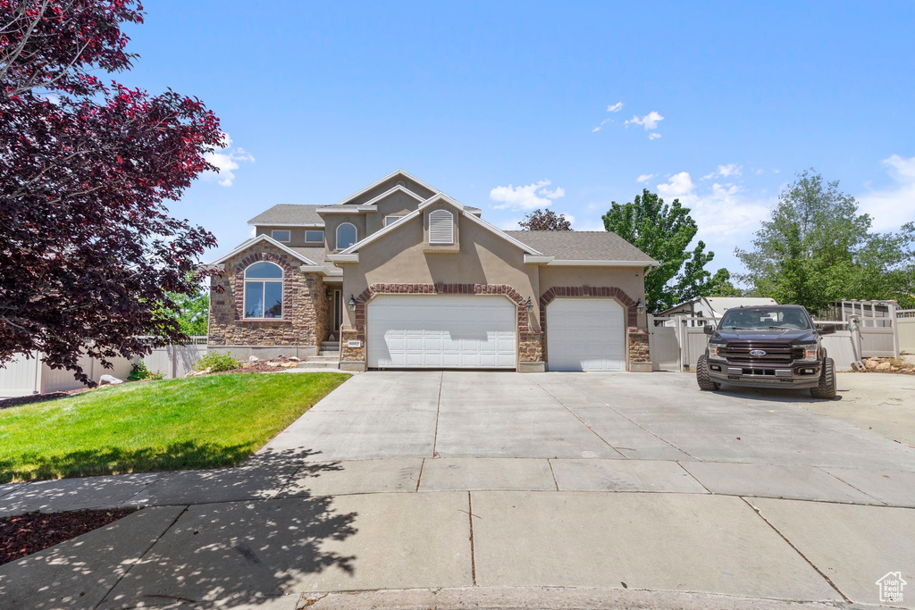 View of front facade with stucco siding, concrete driveway, stone siding, and an attached garage