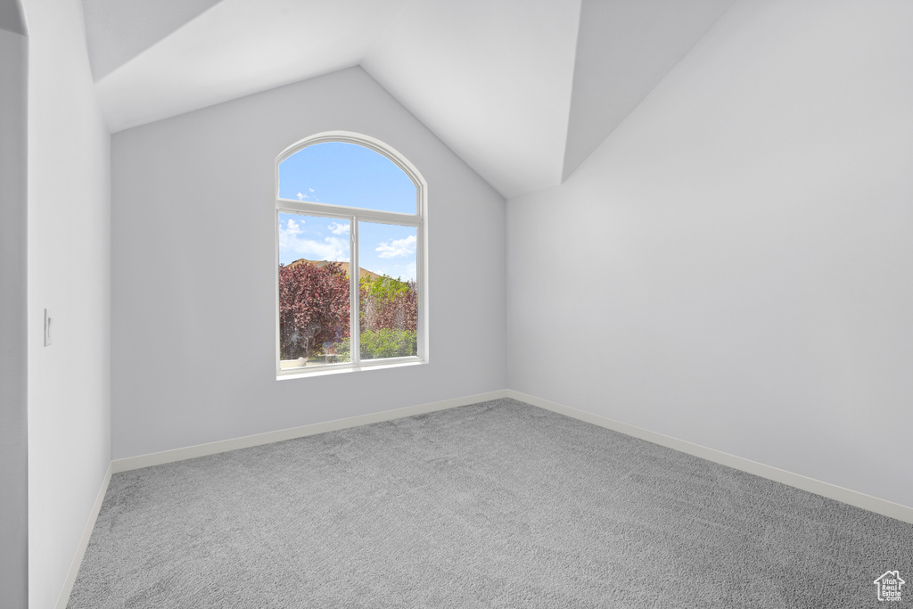Carpeted empty room with lofted ceiling and baseboards