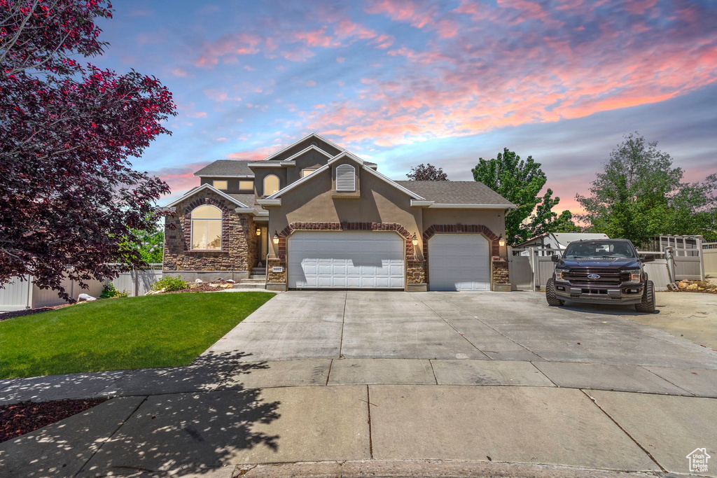 Traditional home featuring stucco siding, concrete driveway, stone siding, and an attached garage