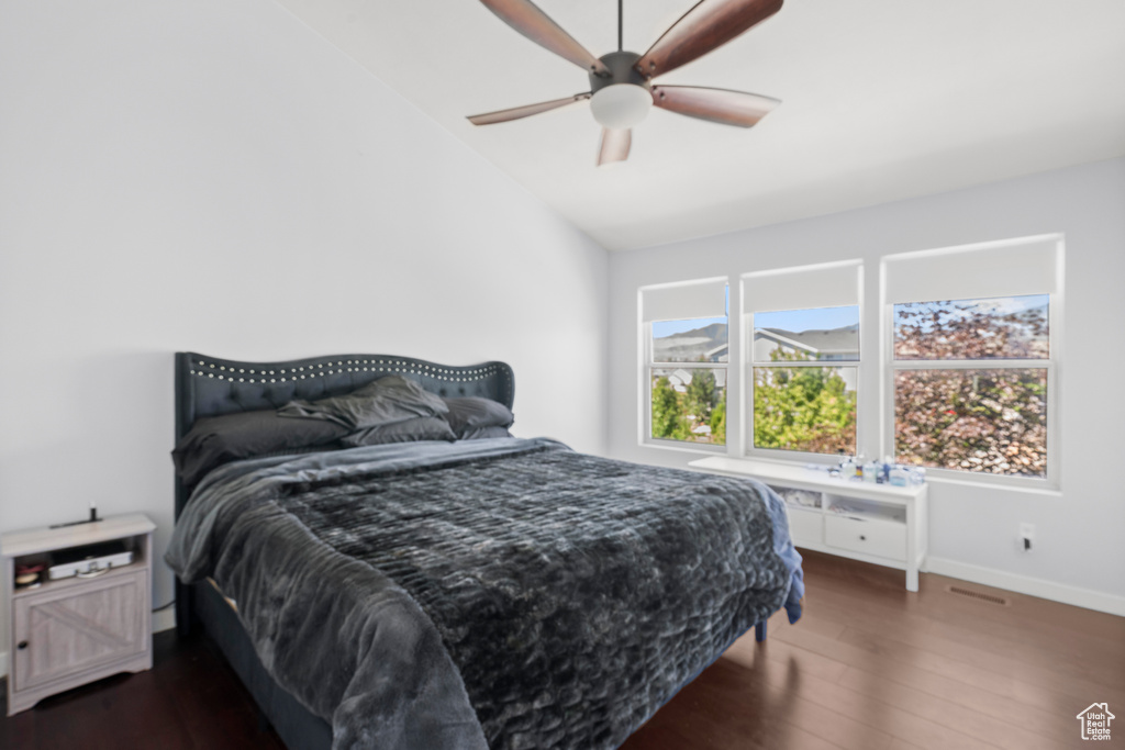 Bedroom featuring dark wood-style floors, lofted ceiling, baseboards, and ceiling fan