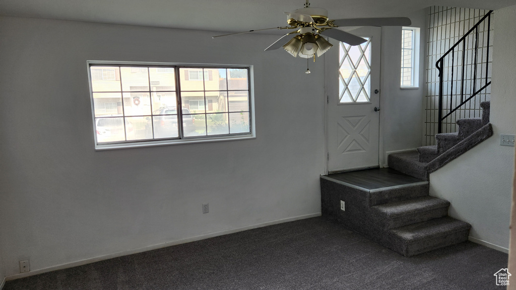 Foyer featuring a ceiling fan, stairway, and carpet flooring