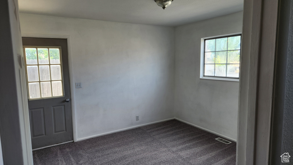 Unfurnished room featuring dark colored carpet and baseboards