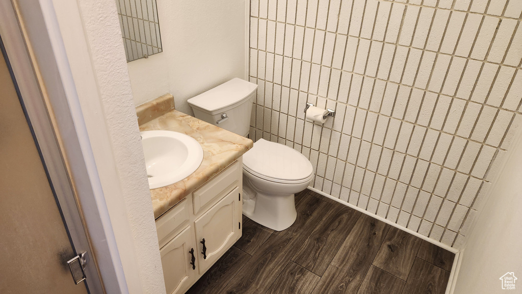 Half bathroom featuring vanity, toilet, and wood finished floors
