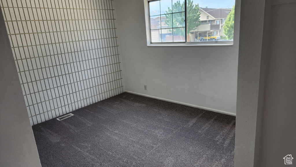 Empty room featuring dark carpet and baseboards