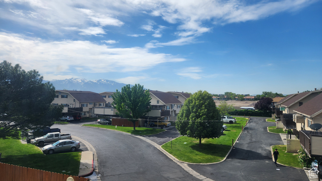View of asphalt road featuring a residential view, curbs, and a mountain view