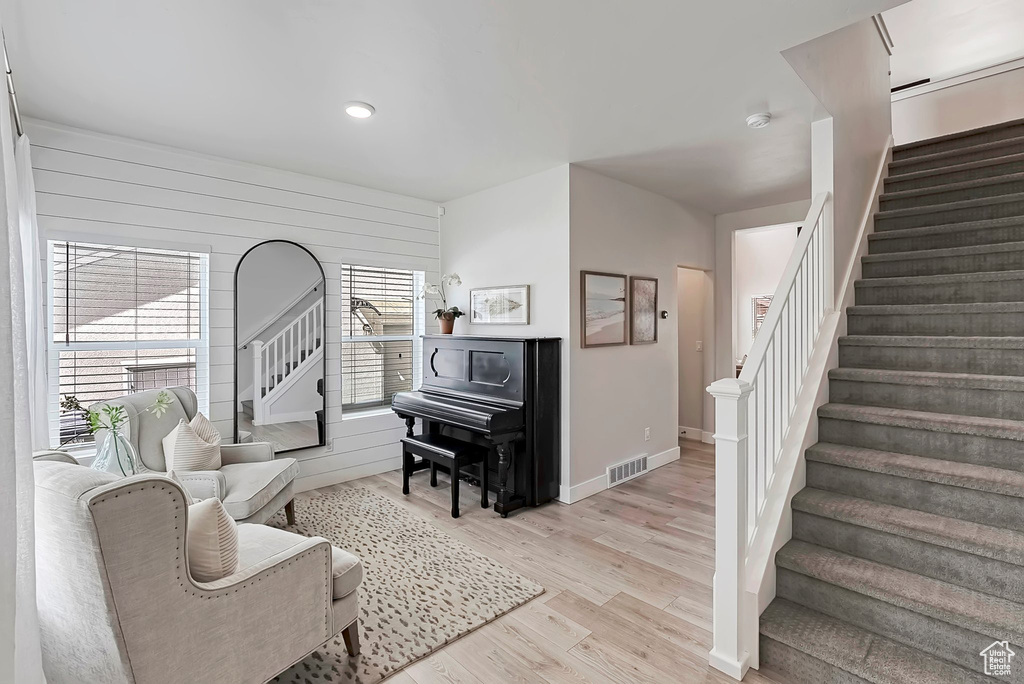 Living area with stairs, light wood finished floors, wooden walls, baseboards, and recessed lighting