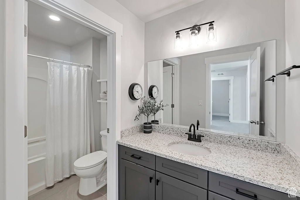 Bathroom featuring toilet, vanity, tile patterned flooring, and shower / bath combo with shower curtain