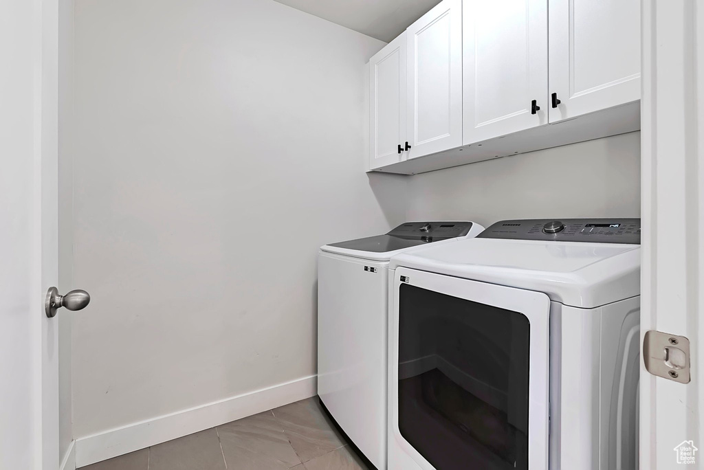 Washroom with washing machine and dryer, cabinet space, and baseboards