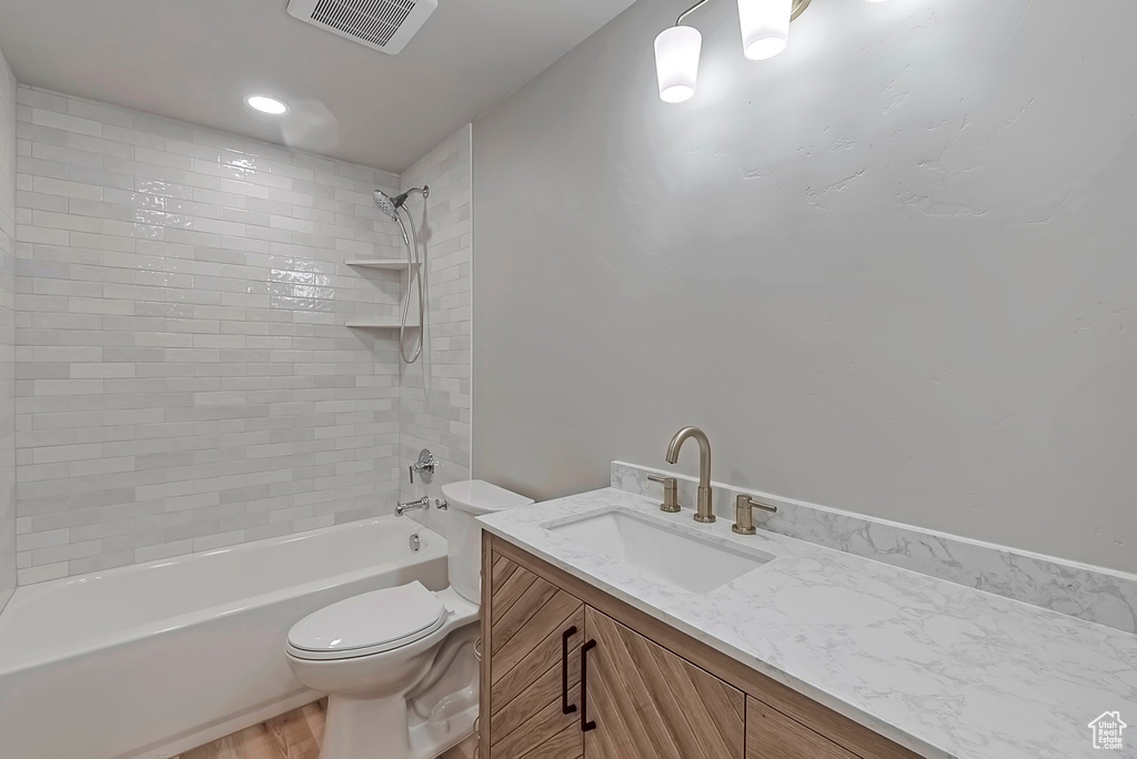 Bathroom featuring toilet, vanity, shower / washtub combination, and wood finished floors