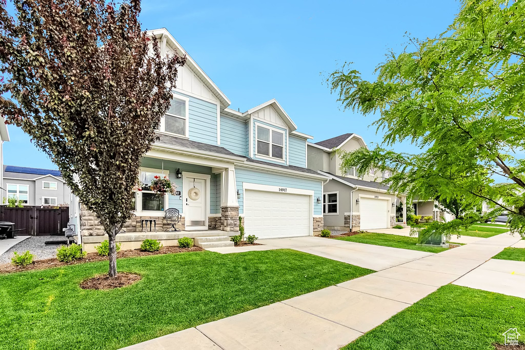View of front of property with an attached garage, board and batten siding, driveway, a porch, and stone siding