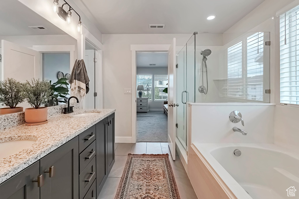 Ensuite bathroom with a stall shower, double vanity, a garden tub, tile patterned flooring, and baseboards