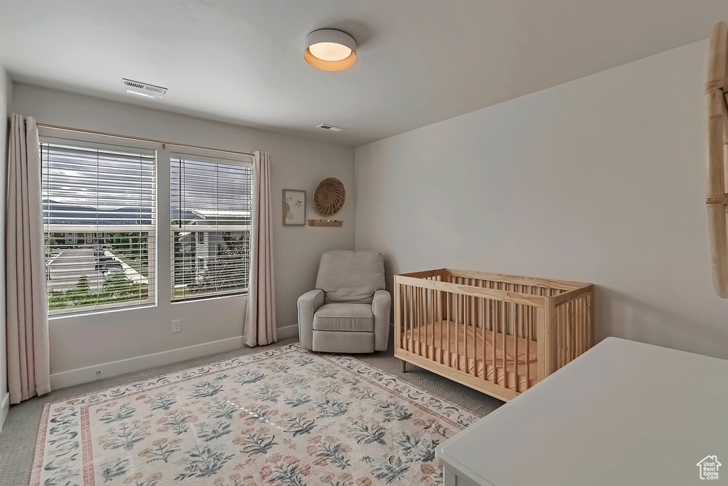 Bedroom with baseboards, a crib, and light colored carpet