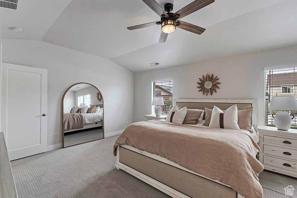 Carpeted bedroom with lofted ceiling, baseboards, multiple windows, and a ceiling fan