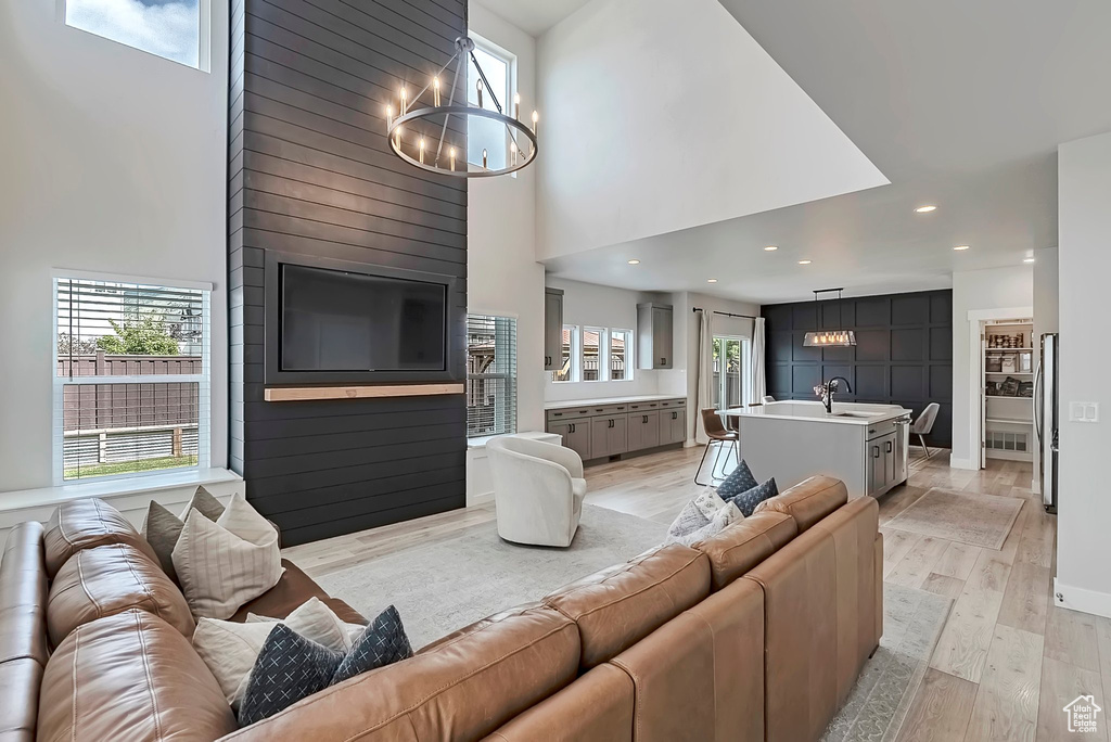 Living room featuring a chandelier, a high ceiling, plenty of natural light, light wood-style flooring, and recessed lighting