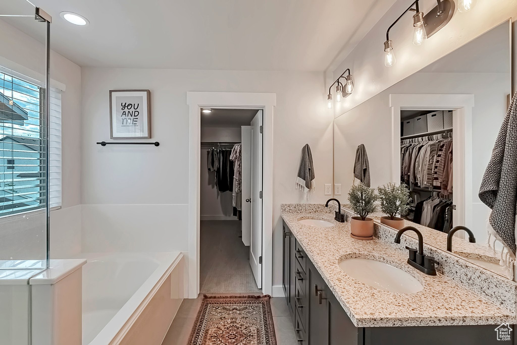 Full bathroom featuring a bath, double vanity, tile patterned floors, a walk in closet, and recessed lighting