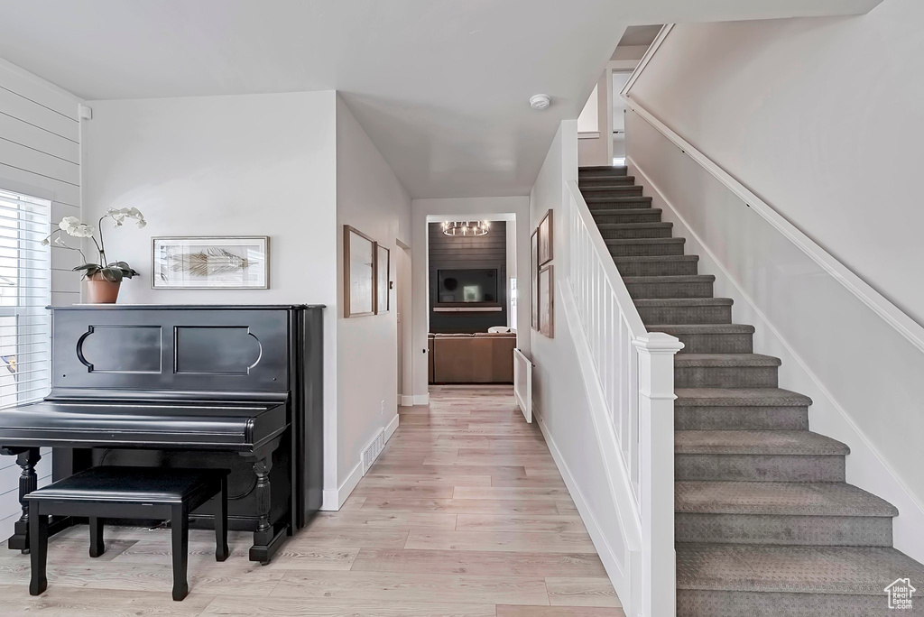 Staircase with wood finished floors and a chandelier