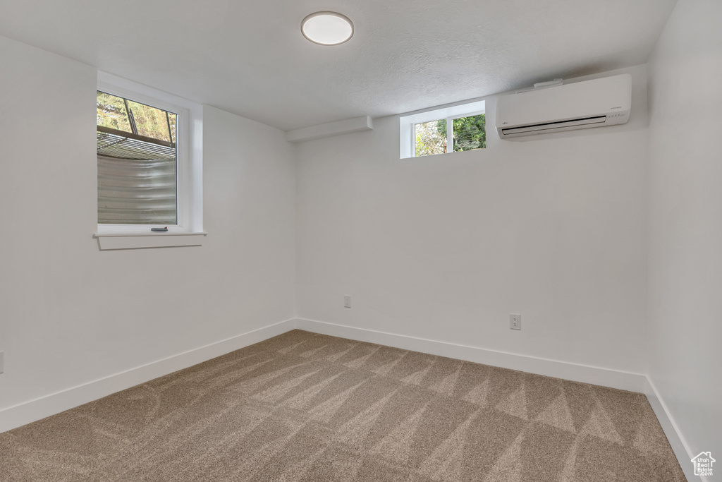 Basement featuring an AC wall unit, carpet flooring, and baseboards