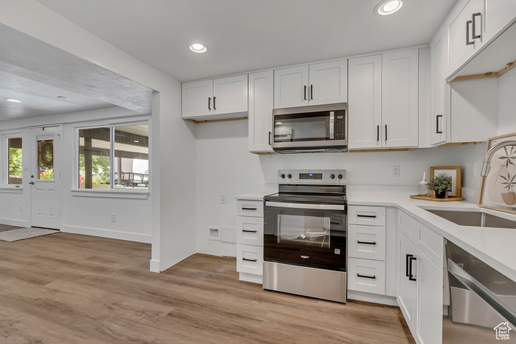 Kitchen featuring stainless steel appliances, a sink, recessed lighting, light countertops, and white cabinets