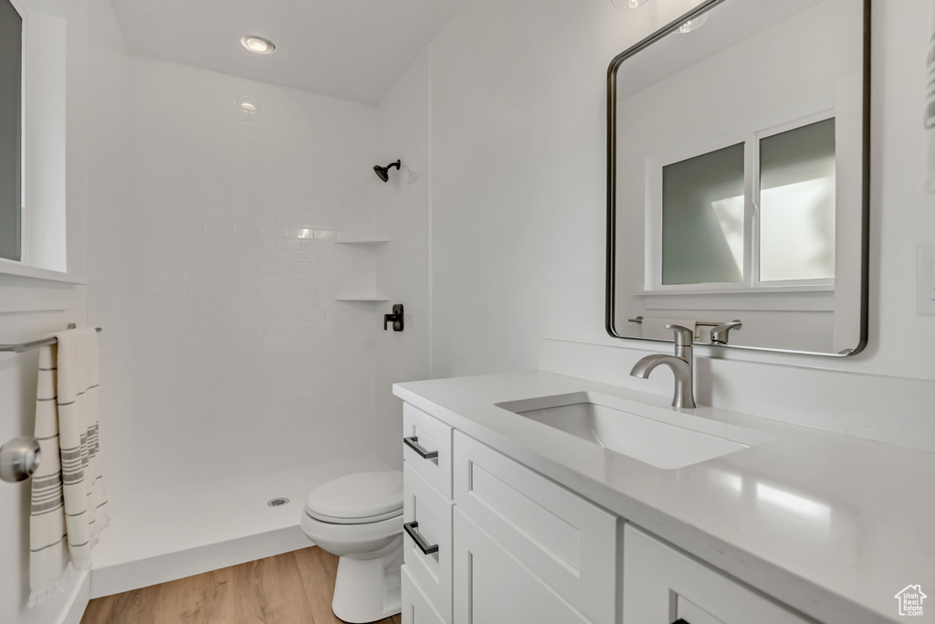 Full bath featuring vanity, a shower stall, toilet, wood finished floors, and recessed lighting