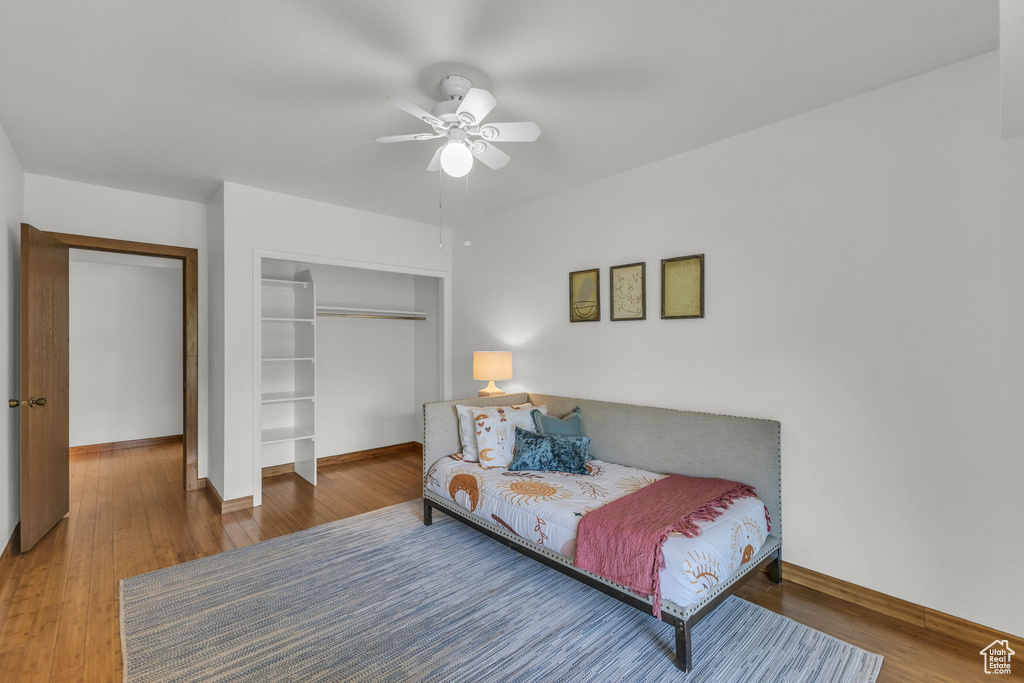 Bedroom with a closet, wood finished floors, baseboards, and ceiling fan