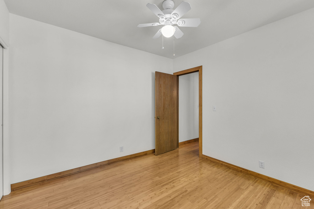Empty room with baseboards, light wood-type flooring, and ceiling fan