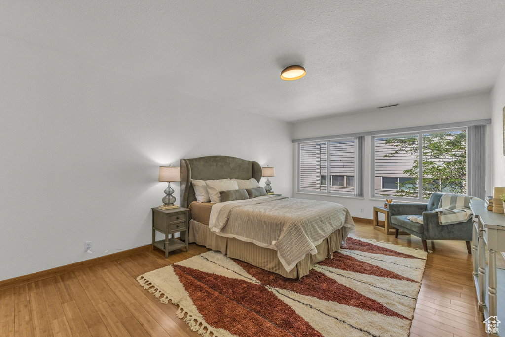 Bedroom featuring wood-type flooring, baseboards, and a textured ceiling