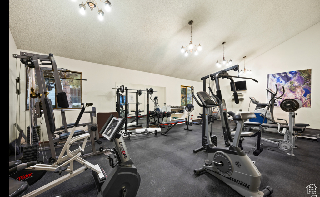 Gym featuring vaulted ceiling, a chandelier, and a textured ceiling