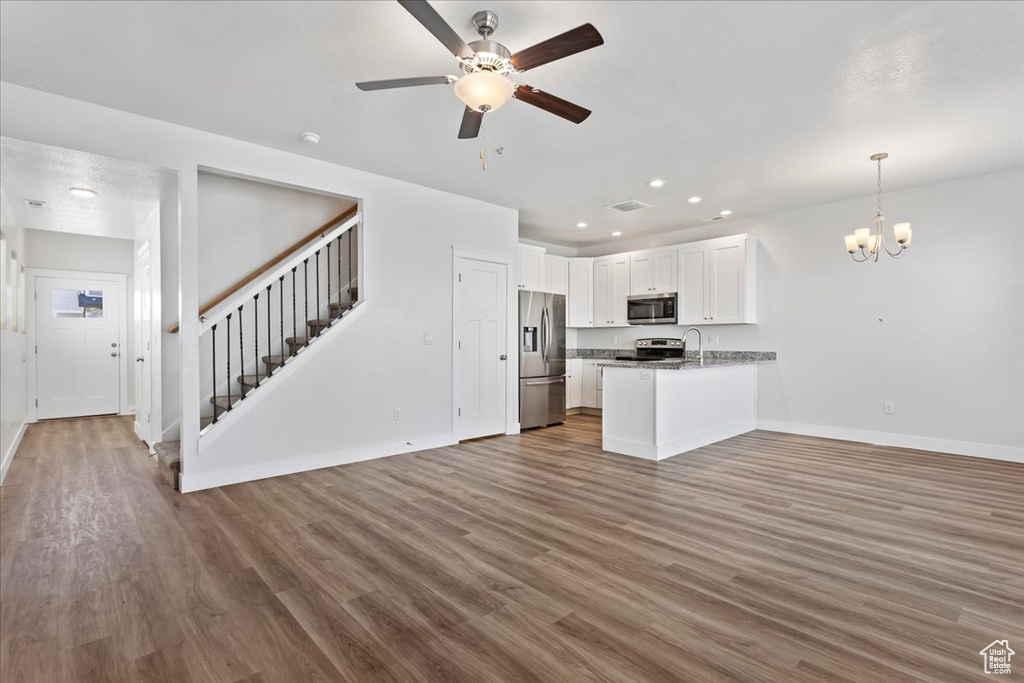 Kitchen featuring appliances with stainless steel finishes, open floor plan, a chandelier, a peninsula, and recessed lighting