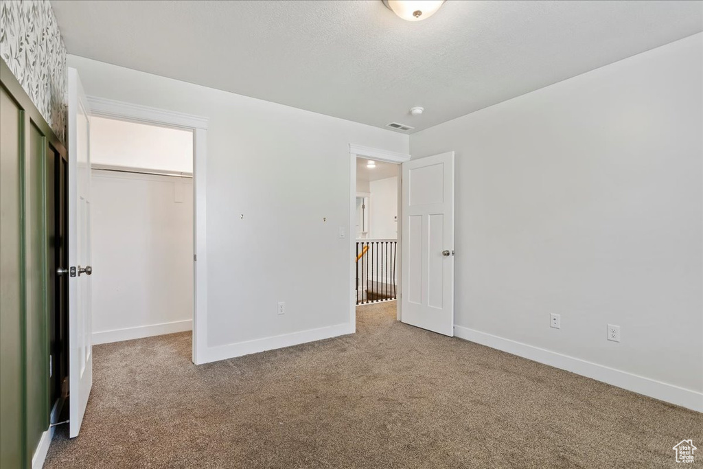 Unfurnished bedroom featuring carpet flooring, baseboards, and a closet
